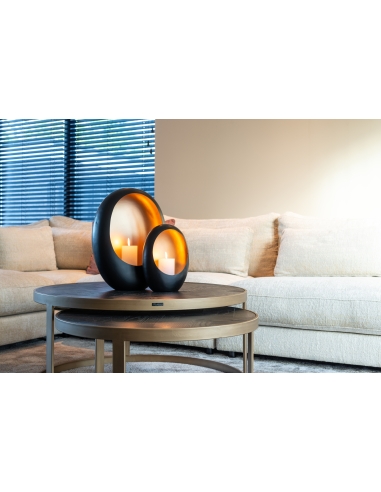 Vista ampla das mesas BLACKBONE diante de um sofá de canto claro, com dois porta-velas pretos e dourados sobre o tampo